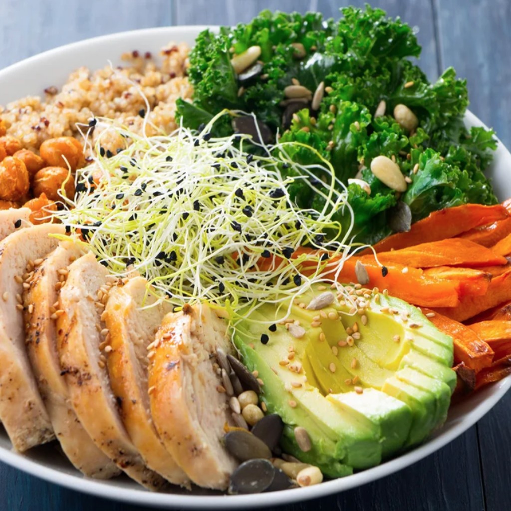 a healthy plate of food consisting of chicken, avocado, carrot, kale, and chickpeas.