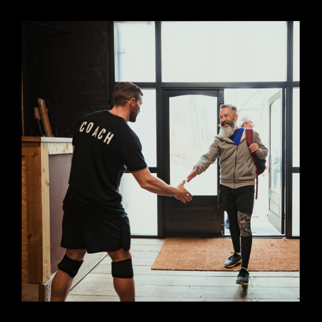 a personal trainer welcoming a client in to the gym