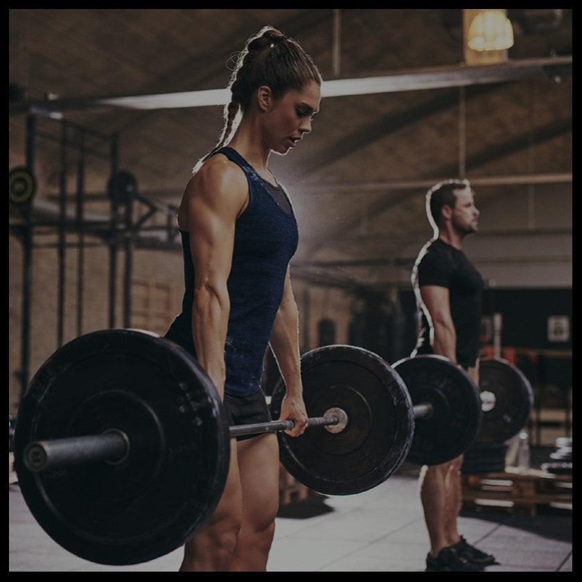 a woman in the gym performing a standing deadlift with a ponytail