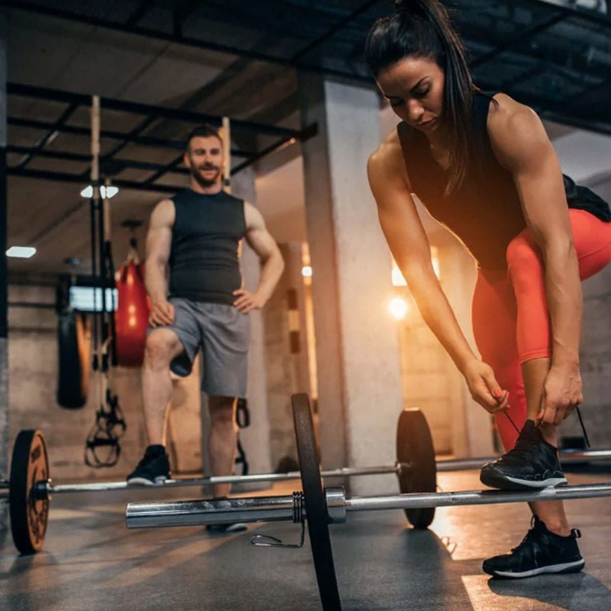 a female gym member tying her shoes during a fitness class.