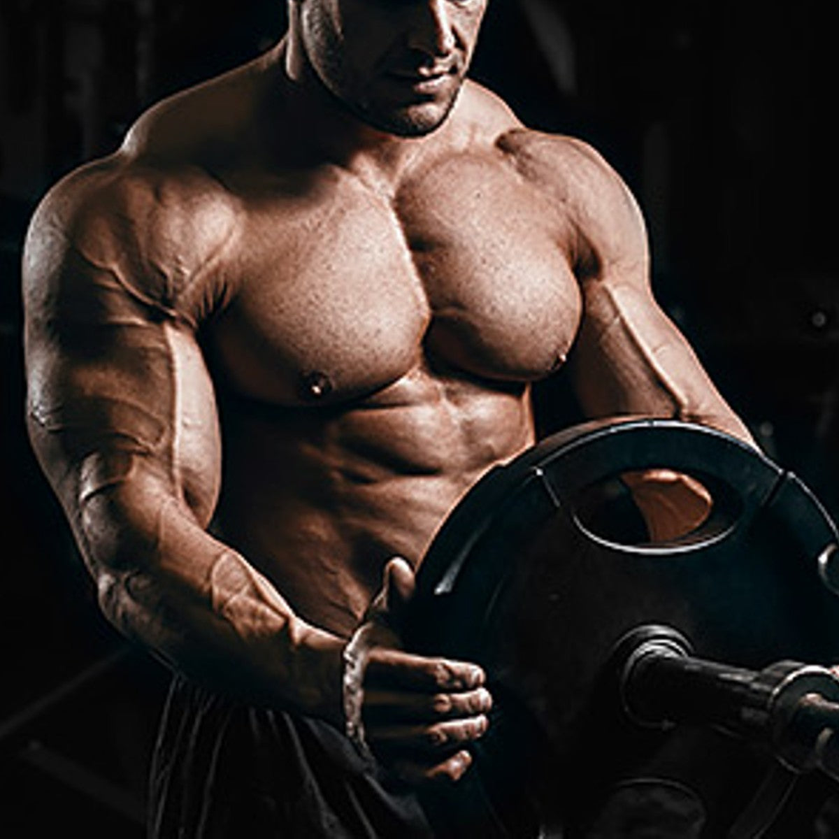 a lean and muscular bodybuilder removing a weight plate from a barbell at a gym.